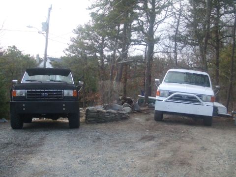 1995 Ford Mustang - Two trucks are parked side-by-side in an outdoor lot with trees and a stone fire pit.