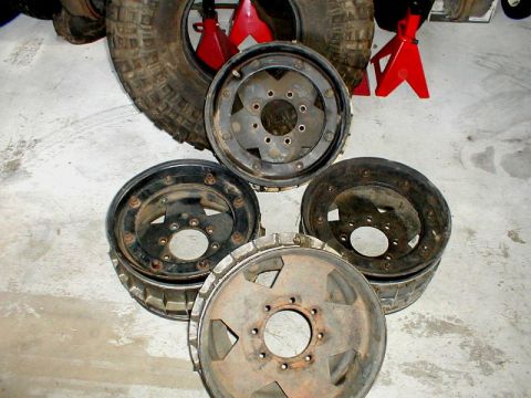 1996 Ford Bronco - A collection of four beadlock wheels and a tire are displayed on a concrete floor, possibly in a garage or workshop.