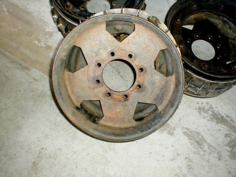 1996 Ford Bronco - Several old, rusty wheel rims are shown on a concrete floor.
