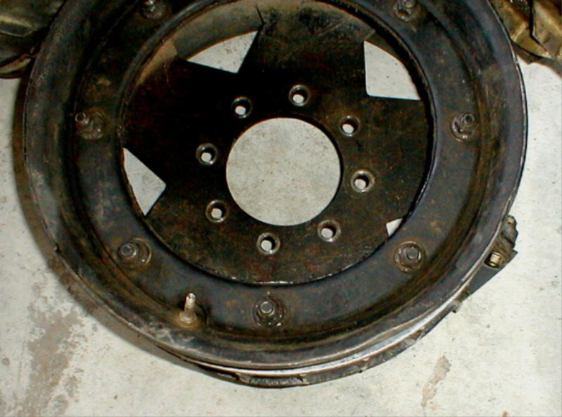close-up of a rusty wheel rim with a tire bead and lug nuts