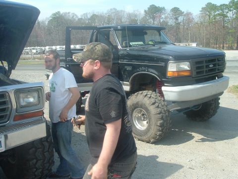 1996 Ford F-150 - Two men stand near a black Ford F-series truck with lifted suspension and large tires.
