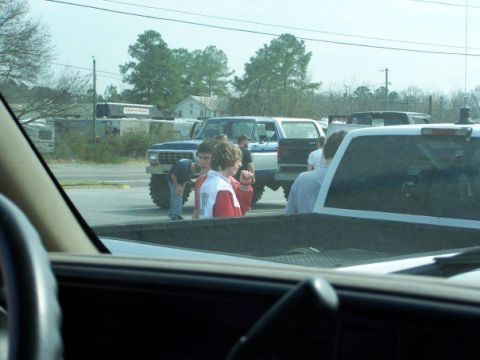 1996 Ford F-150 - A lifted pickup truck with large tires is parked on a street, with several people gathered around it.