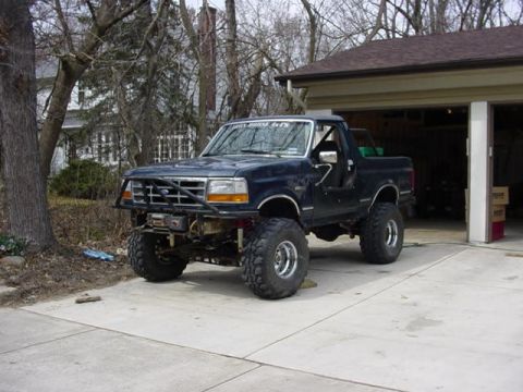 1992 Ford Bronco - This modified Ford Bronco is parked in front of a garage on a cloudy day.