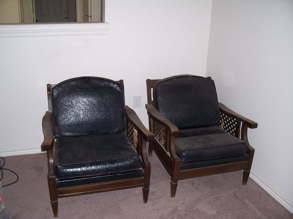 Two dark upholstered armchairs with wooden frames sit on a carpeted floor