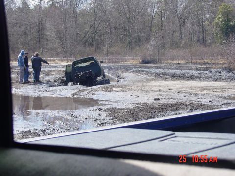 1995 Dodge 1500 - A 1995 Dodge 1500 is stuck in a muddy area with onlookers observing the situation.