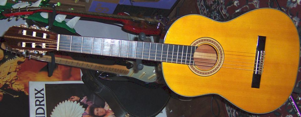Two classical acoustic guitars on a stand next to a Hendrix magazine