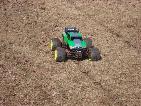 1994 Ford Bronco - A green remote control monster truck sits on a patch of dry grass, its large tires and aggressive stance evident.