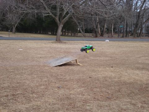 1994 Ford Bronco - RC monster truck airborne after launching off a homemade ramp in a grassy yard.