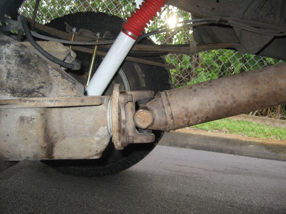 Close-up of a vehicle's rear axle and driveshaft with a red and white shock absorber