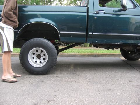 1974 Ford F-100 - Side view of a green pickup truck with aftermarket wheels and tires, indicating a lifted suspension.