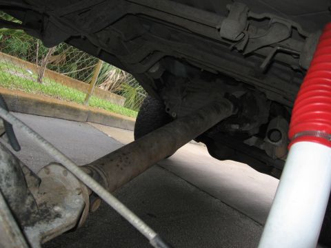 1974 Ford F-100 - Underside view of a truck's driveline components, including the driveshaft and differential, with a prominent red and white shock absorber…