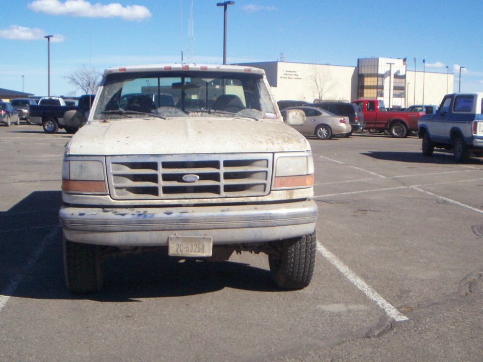 White 1992 Ford F-250 pickup truck, front view, dirty condition, parked in a lot