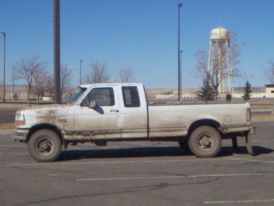 White 1992 Ford F-250 pickup truck, side view, covered in mud