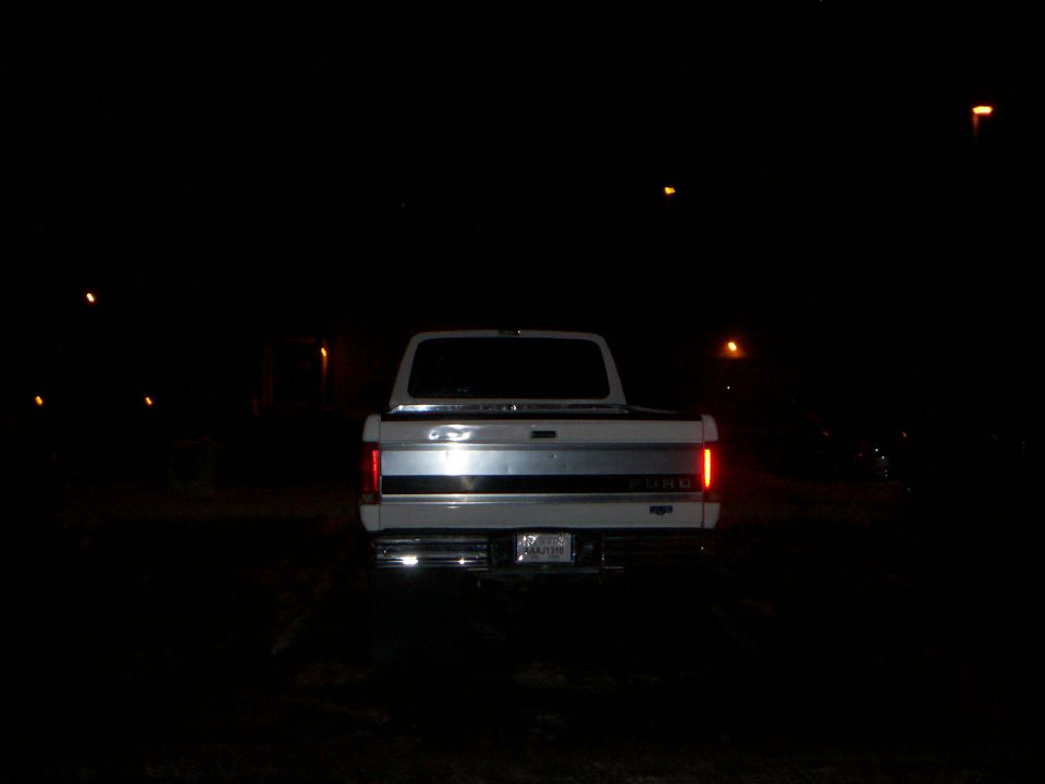 Rear of a white 1992 Ford F-250 pickup truck with taillights on