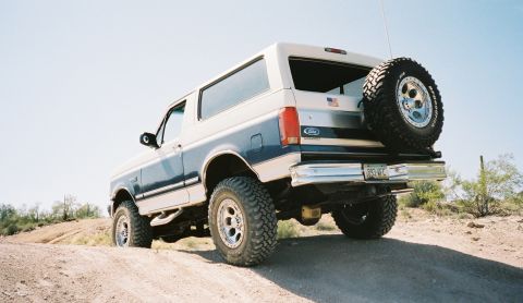 1996 Ford Bronco - This two-tone Ford Bronco is parked on a dusty trail under a clear sky.