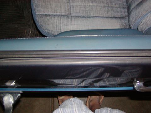 1988 Ford Bronco - Interior view of a car door sill and seat fabric, with feet visible underneath.