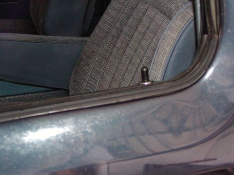 1988 Ford Bronco - Close-up view of the interior door lock pin and window seal on a vehicle.