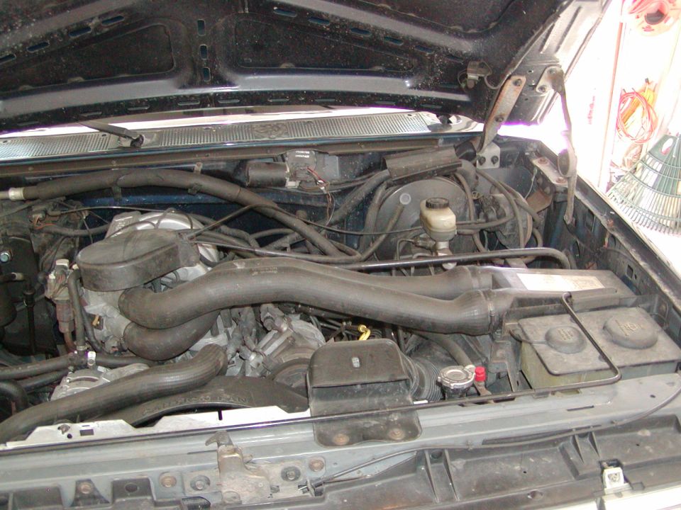 Engine bay of a truck with hood open in a garage