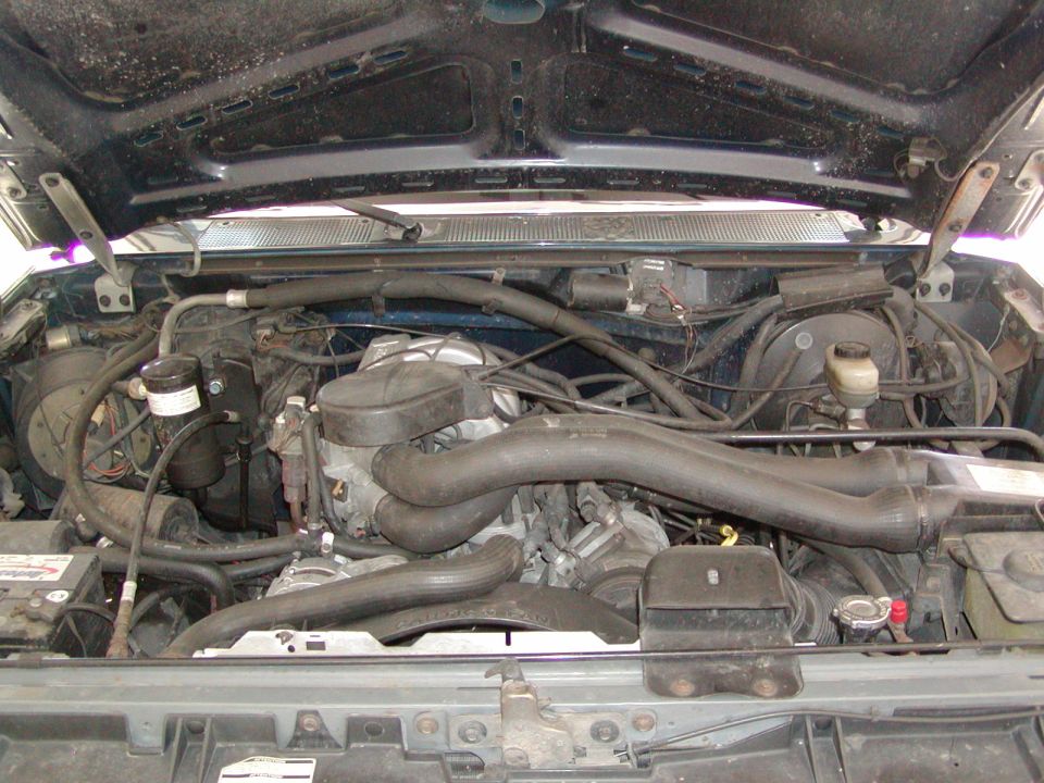 Open hood view of a truck engine bay with radiator and intake tube