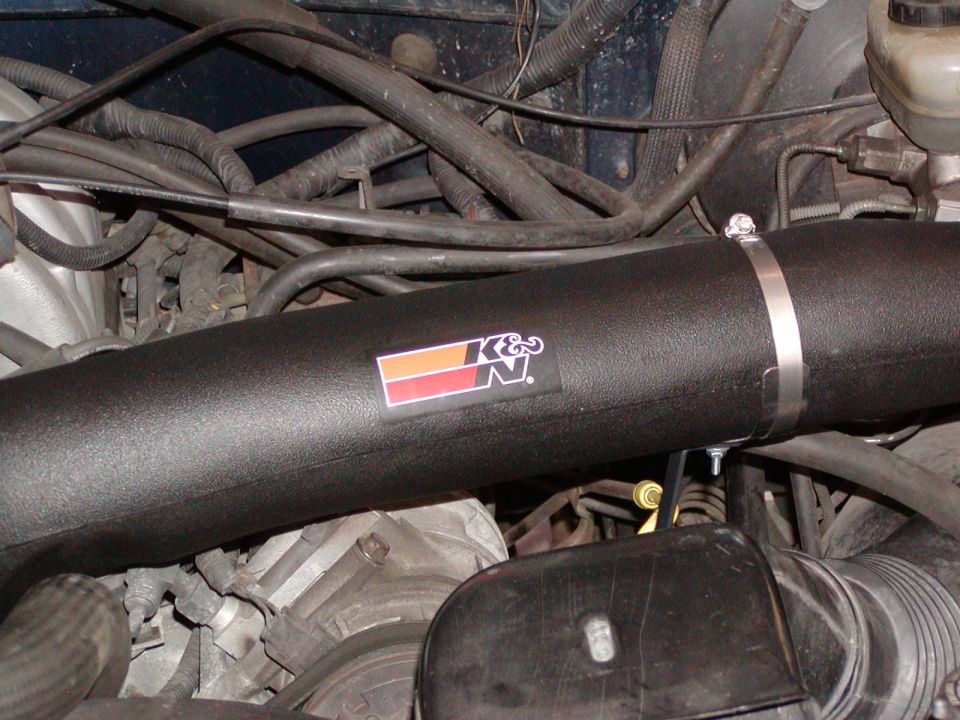 Black K&N intake tube with logo decal clamped in an engine bay