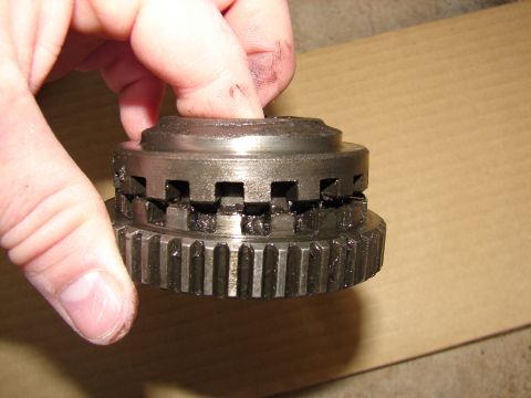 1996 Ford Bronco - A close-up of a metal gear component, possibly for a transmission or hub, being held by a person's hand.