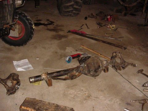 1992 Ford Bronco - A disassembled rear axle assembly lies on the floor, surrounded by tools and a grinder, suggesting a repair or modification in progress.
