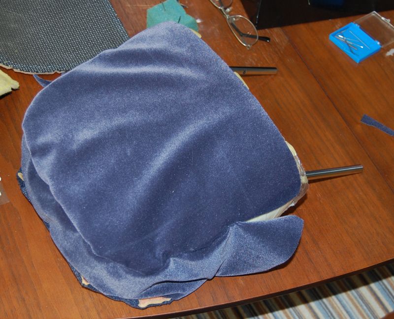 blue velvet car headrest on a wooden table with sewing supplies nearby