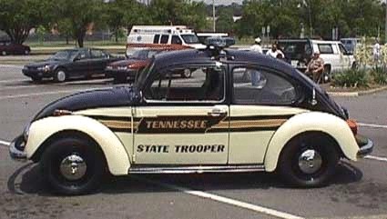 1972 Ford Ranchero - A black and white Volkswagen Beetle marked as a Tennessee State Trooper vehicle is parked in a lot with other vehicles.