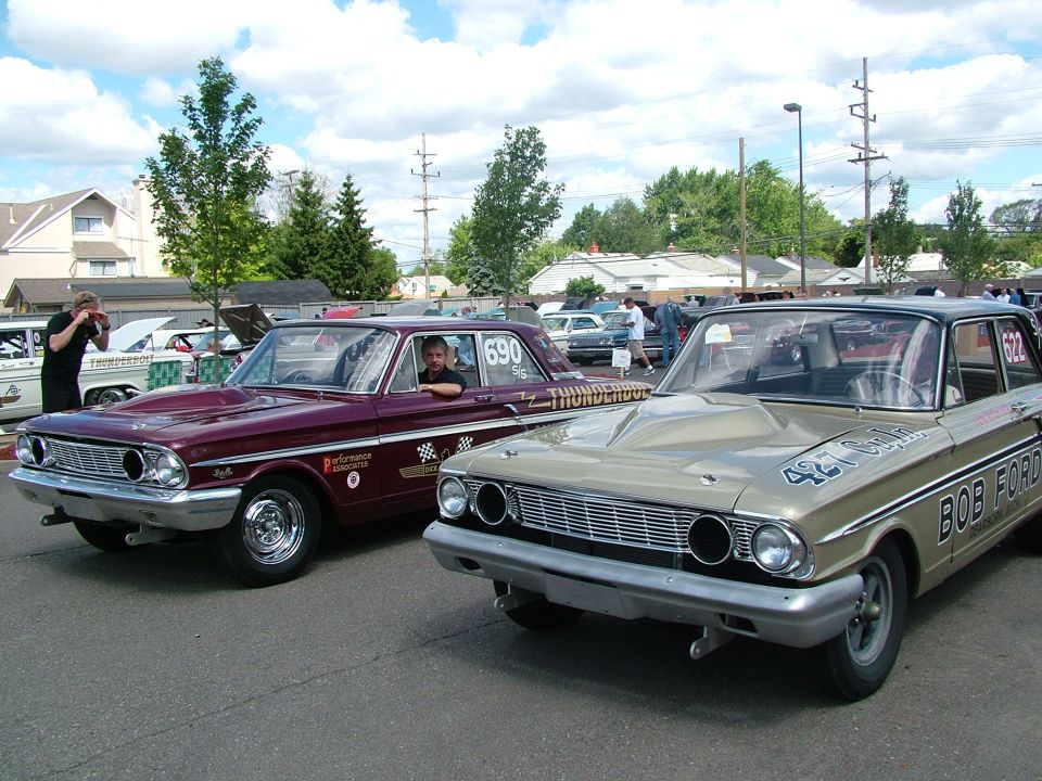 Two Ford sedans, one maroon with 'Thunderbolt' on the side, the other tan with 'Bob Ford' on the side. Both appear to be from the early 1960s