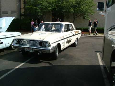 1972 Ford Ranchero - A white 1964 Ford Fairlane sedan, modified for racing, is parked next to another vehicle.