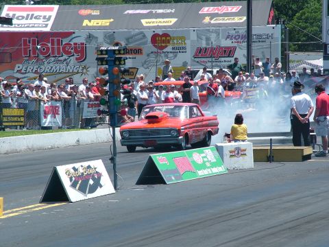 1972 Ford Ranchero - A red 1963 Ford Falcon drag car prepares for a race, surrounded by spectators and racing infrastructure.