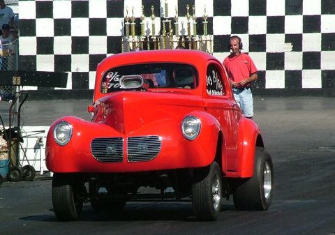 1972 Ford Ranchero - A drag racer sits on the track, ready for competition, with a checkered flag backdrop and trophies displayed.