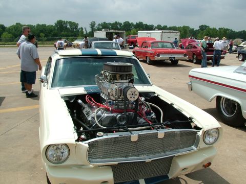 1972 Ford Ranchero - A heavily modified 1965 Ford Mustang coupe is displayed with its hood open, revealing a large supercharger and custom engine components.