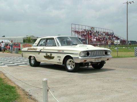 1972 Ford Ranchero - A vintage drag car, possibly a 1964 Ford Falcon, sits on the track with racing decals and a hood scoop.
