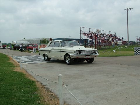 1972 Ford Ranchero - A white 1964 Ford Falcon sedan is on a drag strip with spectators in the background.