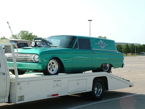 1972 Ford Ranchero - A heavily modified panel van, likely a Ford Falcon, is loaded onto a tow truck, its prominent supercharger and custom paint.