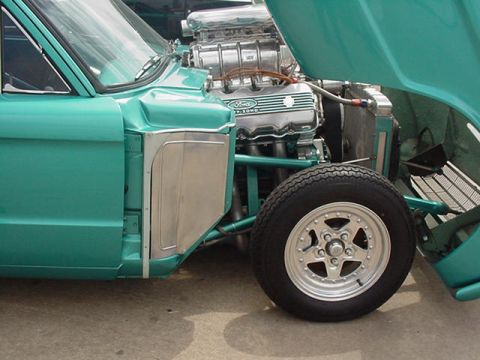 1972 Ford Ranchero - A teal 1972 Ford Ranchero is shown with its hood open, revealing a supercharged V8 engine and a racing wheel.