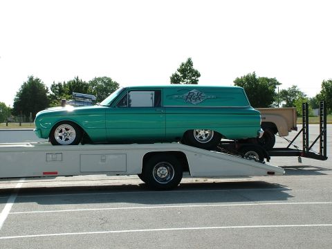 1972 Ford Ranchero - Custom green panel van being transported on a trailer, with a tan pickup truck visible behind.