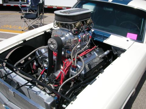 1972 Ford Ranchero - Close-up of a powerful, modified engine with a prominent supercharger and custom wiring under the hood of a white vehicle.