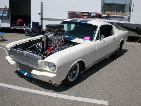 1972 Ford Ranchero - A custom 1965 Ford Mustang with a prominent supercharger and racing stripes is displayed with its hood open.