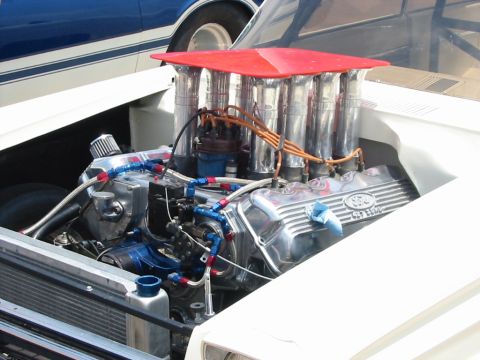 1972 Ford Ranchero - Engine bay of a white vehicle, showing a Ford V8 engine with chrome valve covers and a red air intake system.