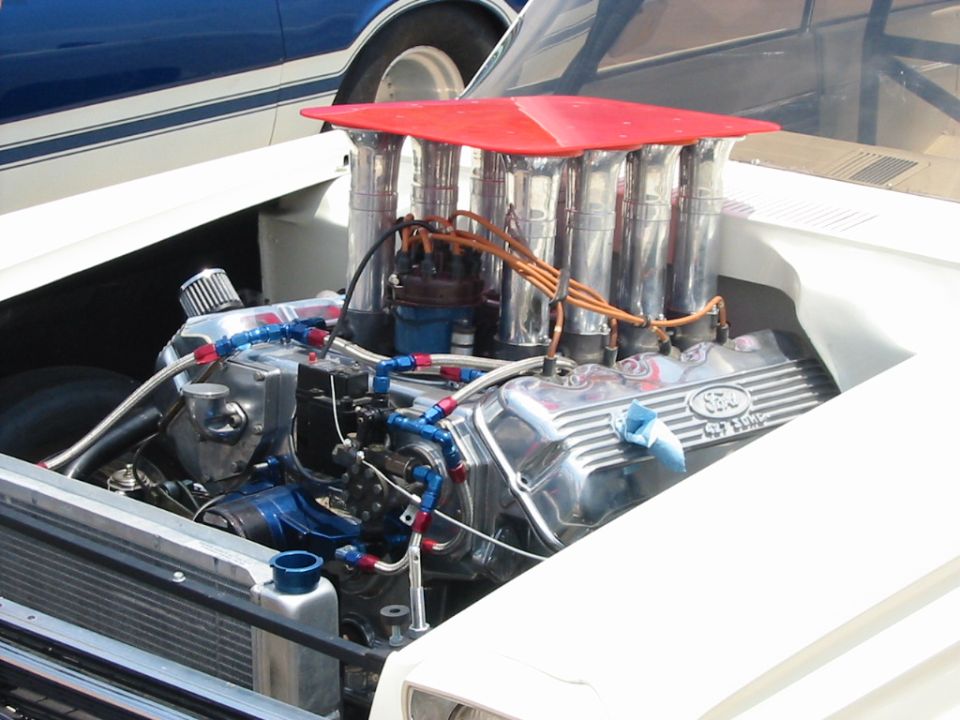 White Ford Ranchero engine bay with chrome Ford valve covers and a red air intake
