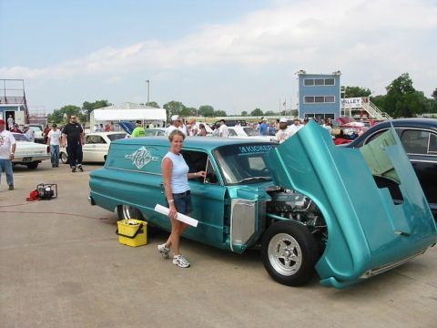 1972 Ford Ranchero - Teal panel van with hood open at an outdoor event. A woman stands next to the driver's door.