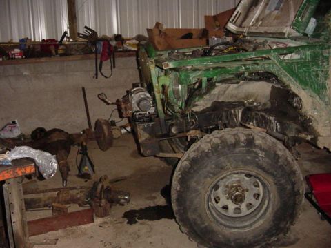 1992 Ford Bronco - Green 4x4 mid-build in a shop, body partially stripped with a solid axle and parts on the floor.