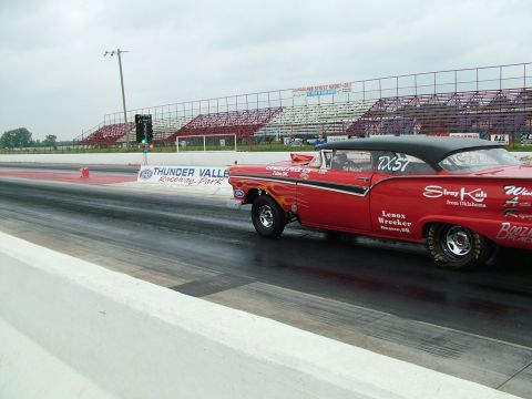 1972 Ford Ranchero - A red 1957 drag car with flame decals and racing sponsorships sits on the track at Thunder Valley Raceway Park.