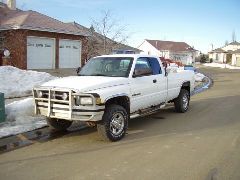 2001 Dodge 2500 - A white 2001 Dodge 2500 pickup truck is parked on a street with snow on the ground and houses in the background.