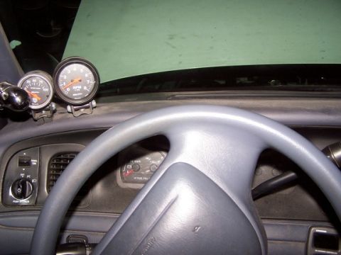 2000 Ford Crown Victoria - Aftermarket gauges are mounted on the dashboard of a vehicle, showing engine RPM and oil pressure.