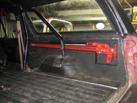 1990 Ford Bronco - Vehicle interior with a Hi-Lift jack mounted on the side panel.