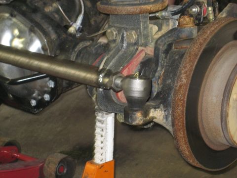 1990 Ford Bronco - This image shows a close-up view of a vehicle's steering and braking components, including a tie rod end and brake rotor.