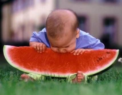 1976 Ford F-150 - A baby enjoys a slice of watermelon outdoors on a sunny day.
